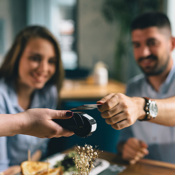 A man with his partner in a restaurant in Ireland paying for their meal