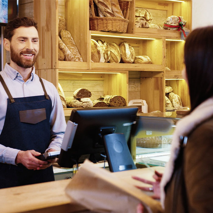 A bakery cashier and customer preparing for a credit card payment at the counter