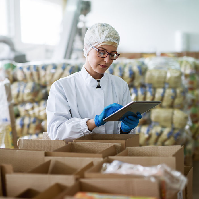 A woman in a white lab coat uses a tablet to analyze data and manage inventory