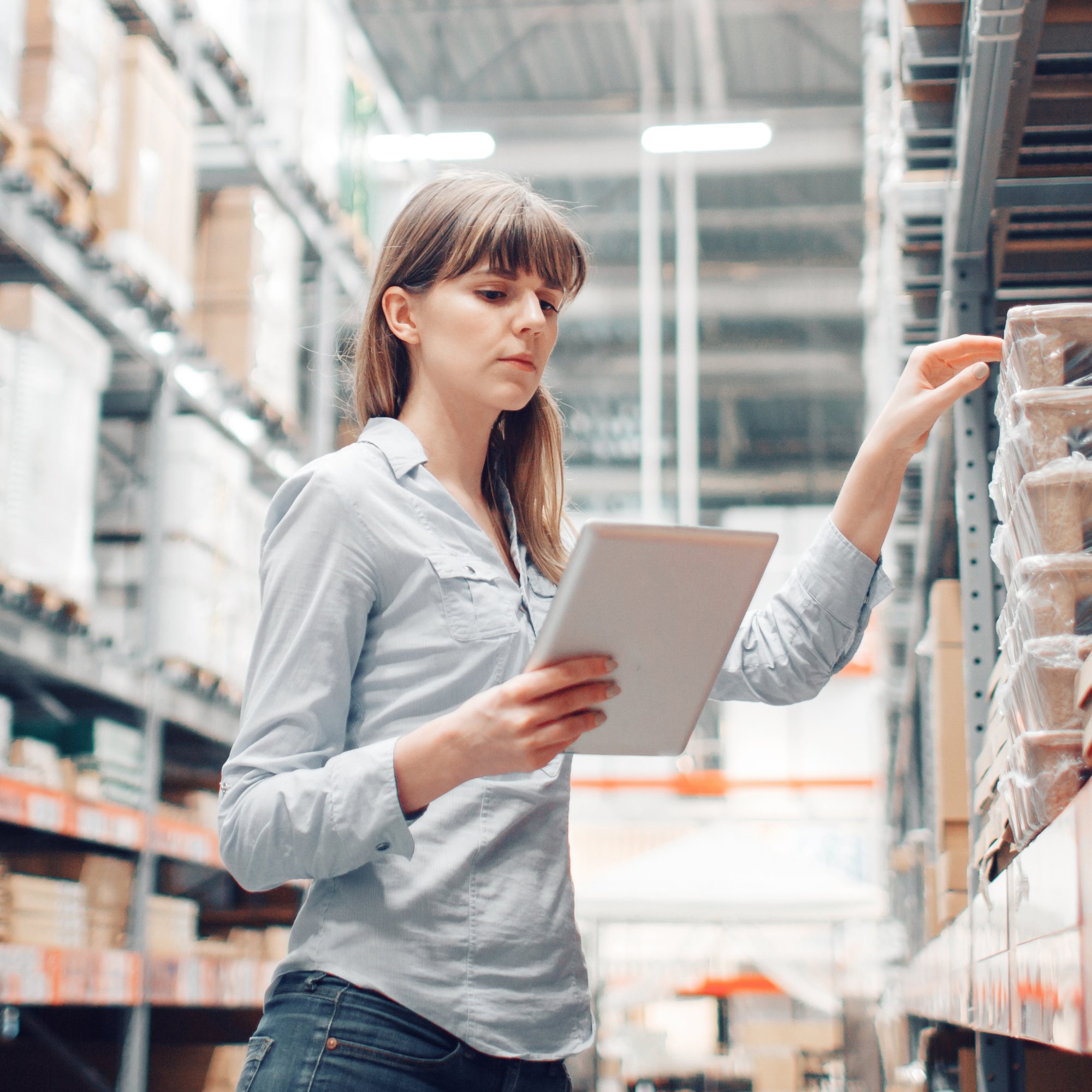 A woman in an Irish warehouse uses a tablet to efficiently manage stock using Kerridge Commercial Systems' ERP