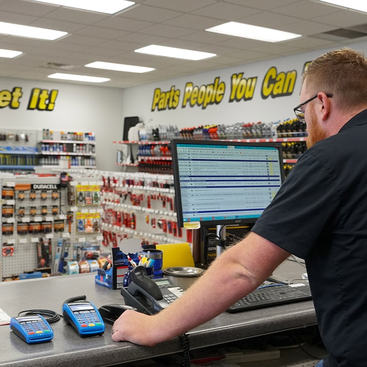 A man working on a computer in an autopart shop.