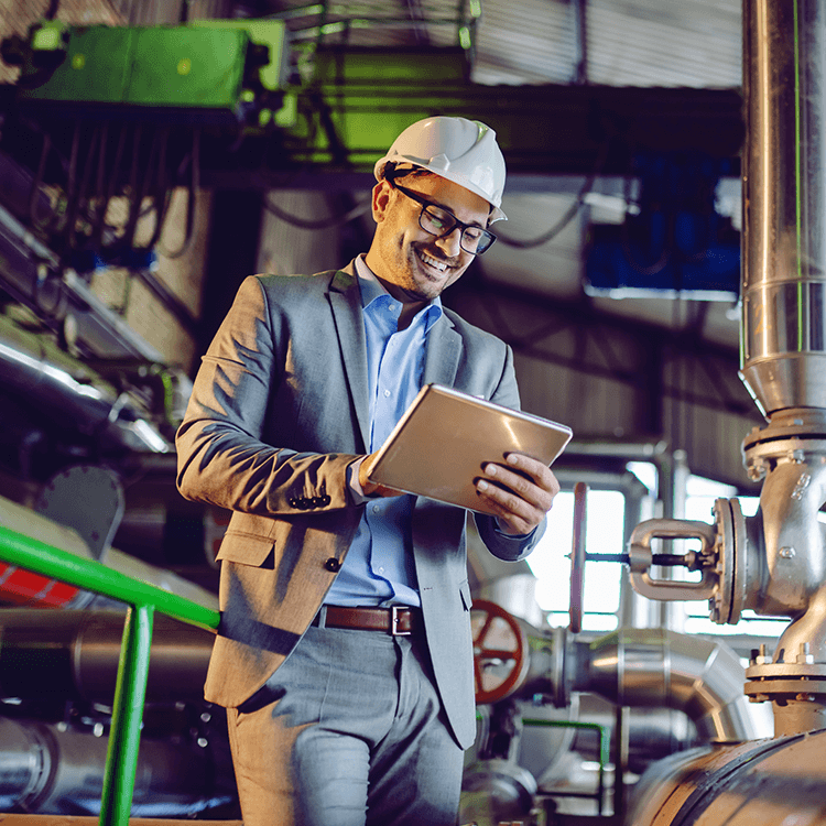 A man in a suit and hard hat stands in front of an Irish factory, managing the sales pipeline.