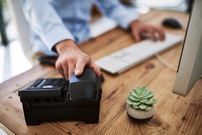 A person's hand on an office telephone.