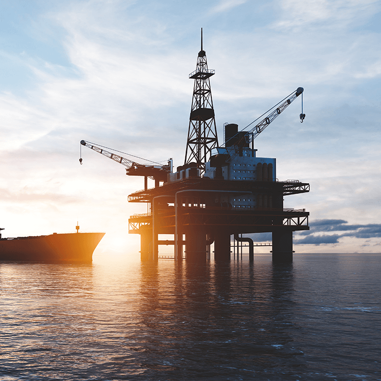 An oil rig in the ocean at sunset