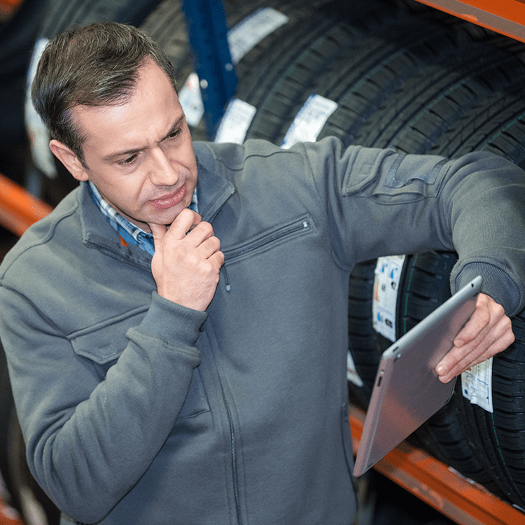 A man using a tablet for tyre management in an Irish tyre store.