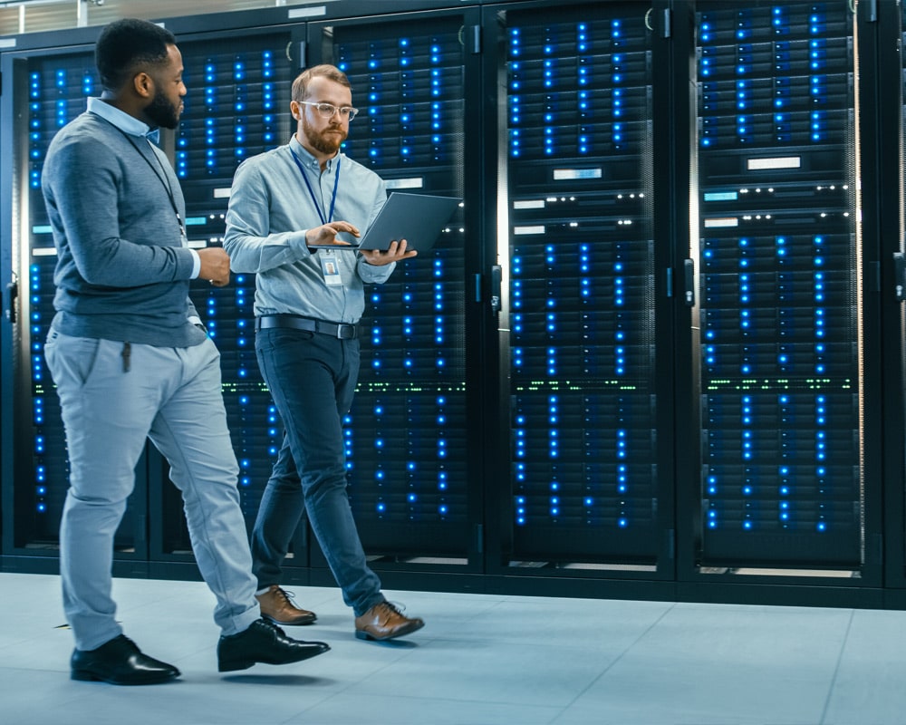 Two men standing in front of servers in an Irish data center, monitoring and maintaining the network infrastructure.