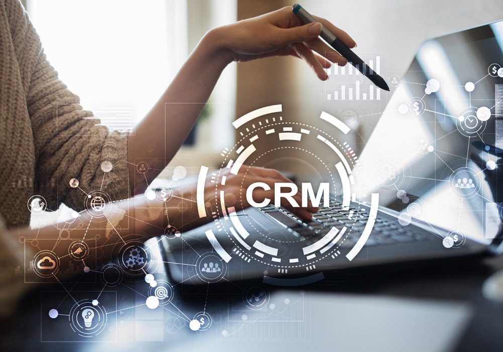 A lady pointing to her laptop, emphasizing the word CRM.