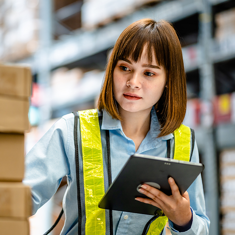 A woman in a safety vest using a tablet for pricing and rebate management.