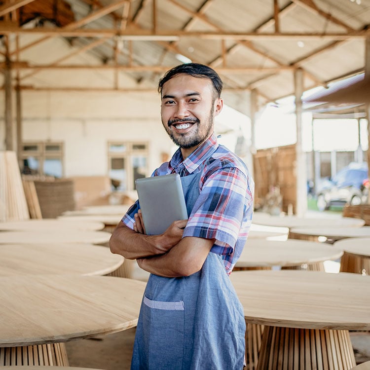 A man with a smile holds a tablet in an Irish industrial workshop, satisfied with KCS's Timber distributors' software