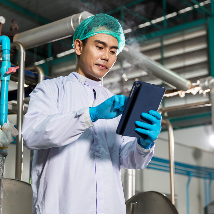 A man in a lab coat analysing warehouse management data on a tablet.