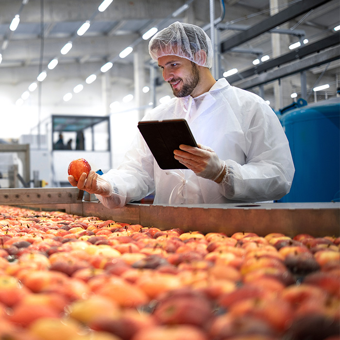 A man in a white coat ensures batch traceability using a tablet for product lifecycle management.