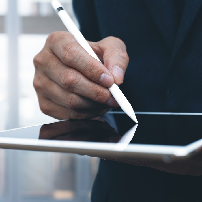 A professional man in a suit writing on a tablet with a pen, showcasing productivity and technology.