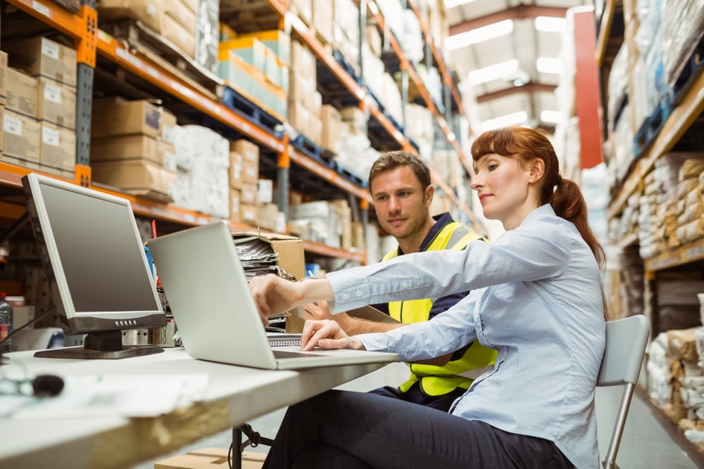 Warehouse worker and manager looking at laptop in a large Irish warehouse