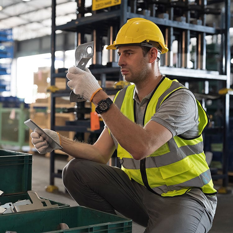 A man working in a warehouse looking a auto parts.