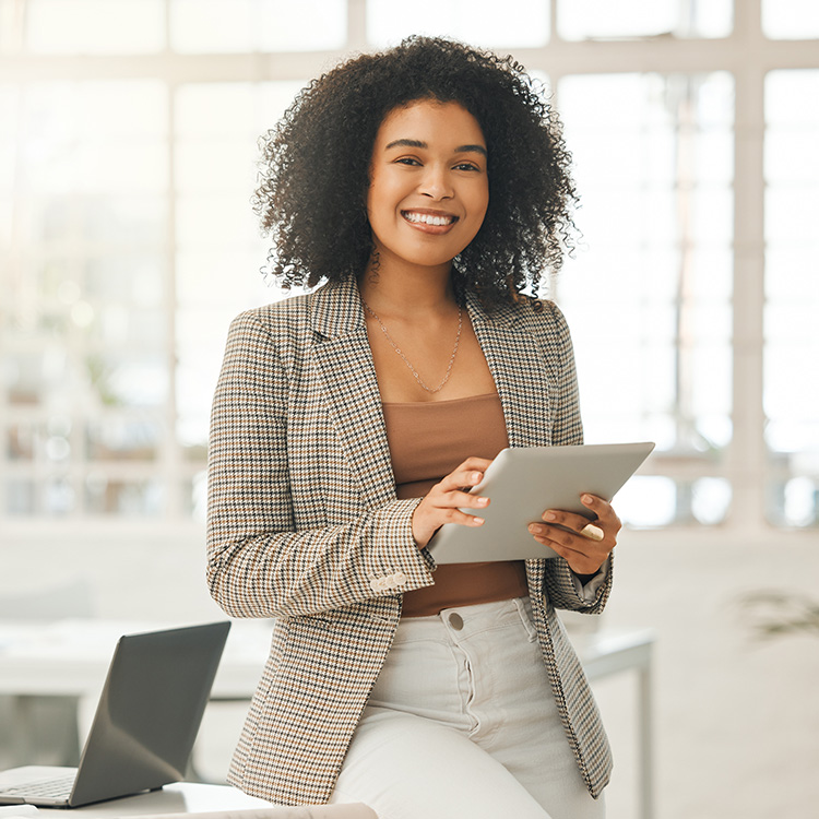 A woman happily holds a tablet computer, radiating joy as she interacts with the device's screen.