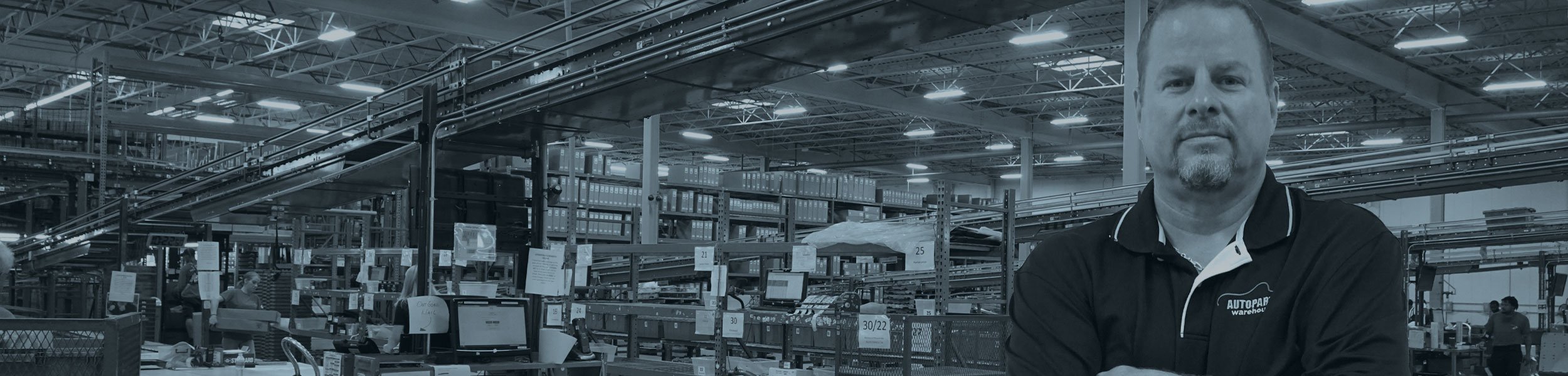 Autopart warehouse employee standing on the foreground of the warehouse