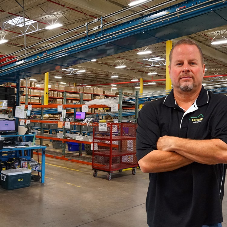 A man standing in a warehouse wth his arms crossed.