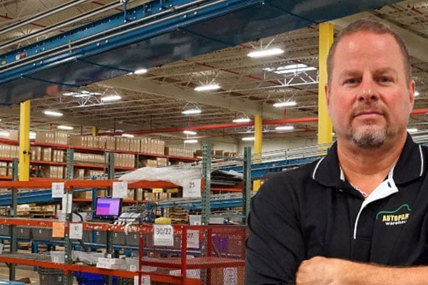 A man standing with his arms crossed in a warehouse