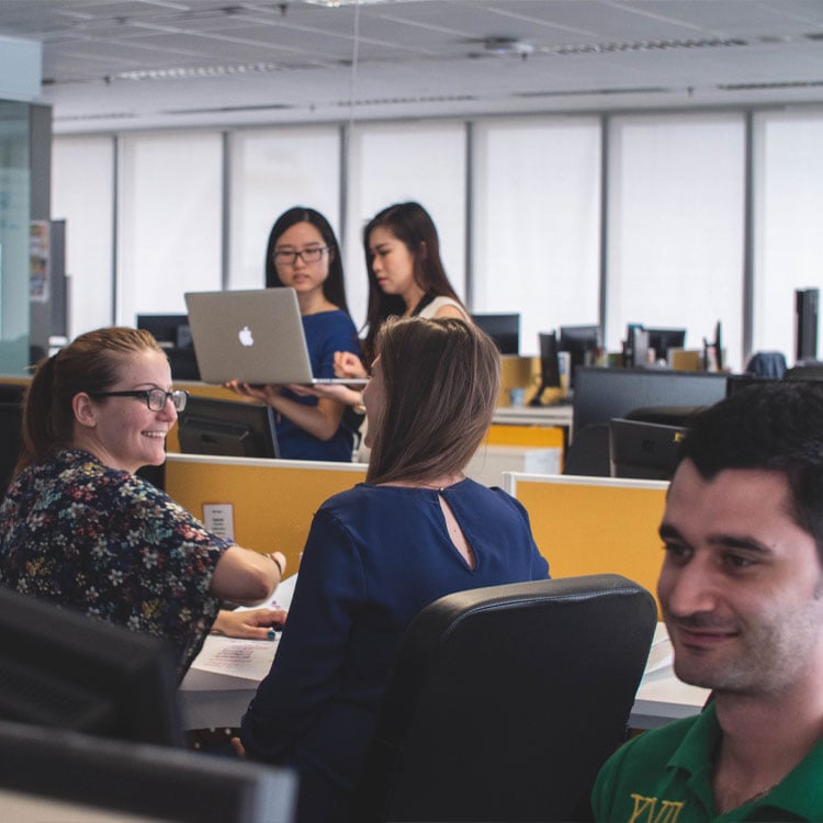 A diverse group of individuals sitting at a desk, engaged in a discussion or working collaboratively.