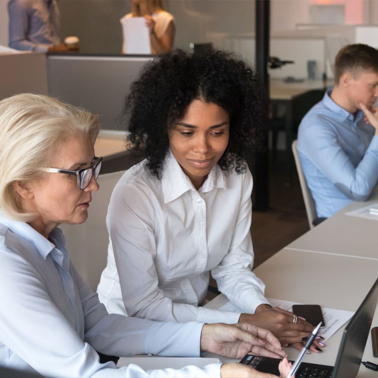 Two employees working together on a laptop.