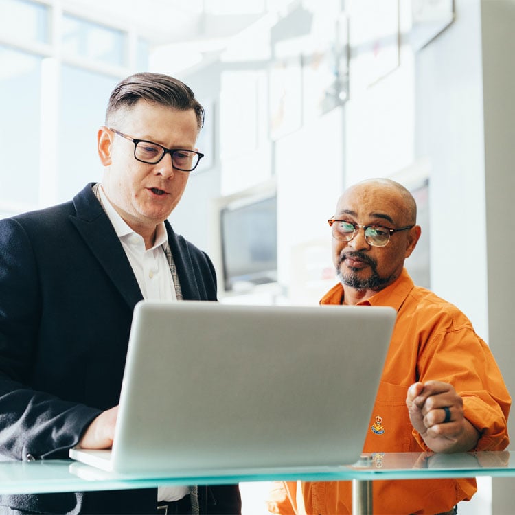 Two employees working together on a laptop.