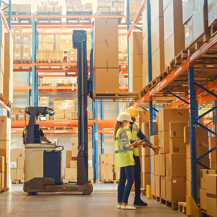 Two people in an Ireland warehouse examining boxes using Kerridge's ERP Software on a tablet.